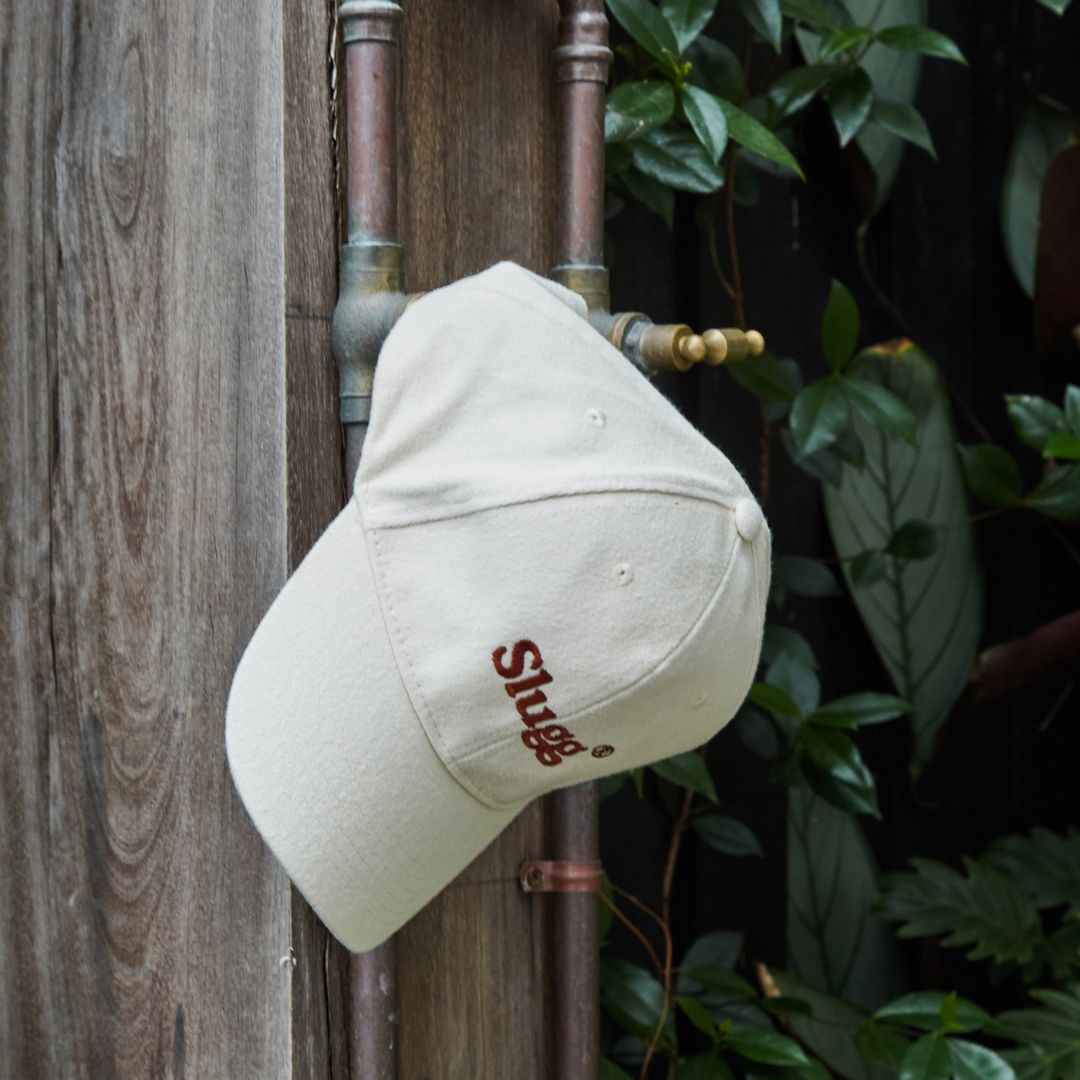 Slugg branded cap hanging on an outdoor tap.