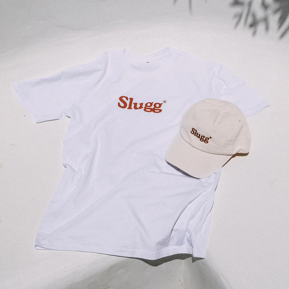 A white t-shirt and beige coloured baseball cap that both say "Slugg".